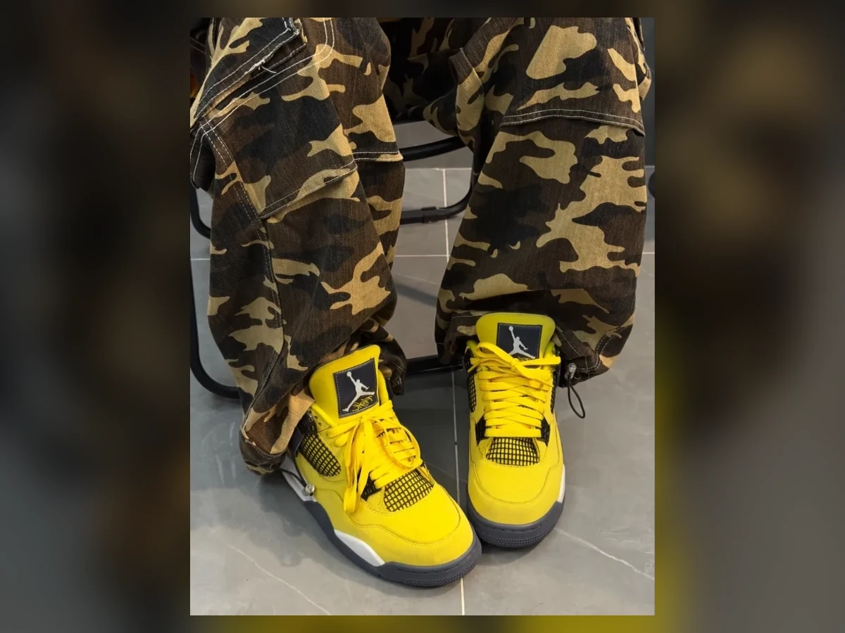 Lower-leg view of the exact yellow Jordan 4 Lightning sneakers