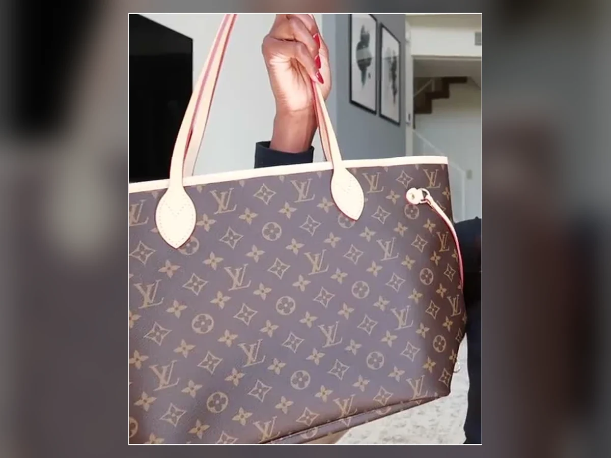 Hand holding the exact classic brown Louis Vuitton Neverfull Monogram